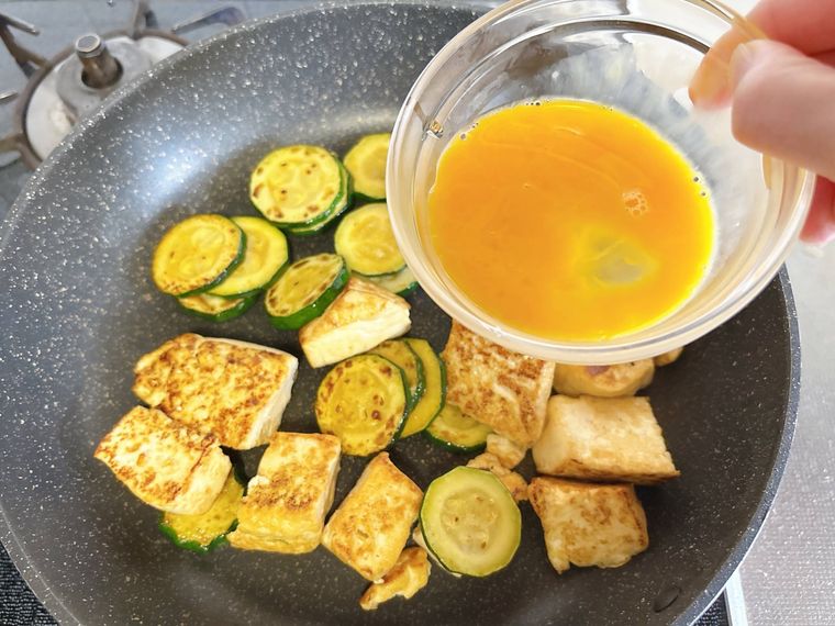 ズッキーニと木綿豆腐に卵を入れる様子