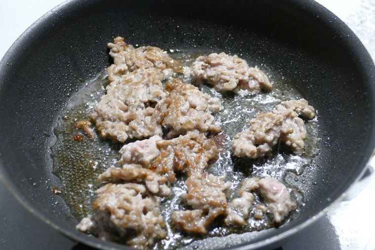 フライパンで豚ひき肉に焼き色をつける様子