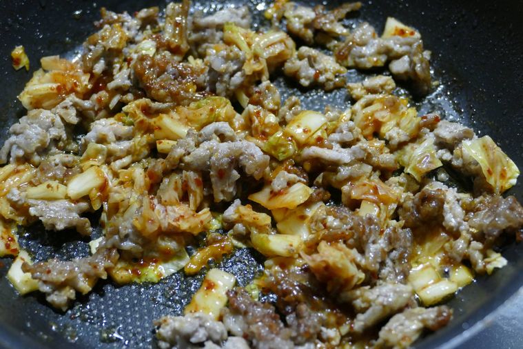 白菜キムチを加えて炒める様子