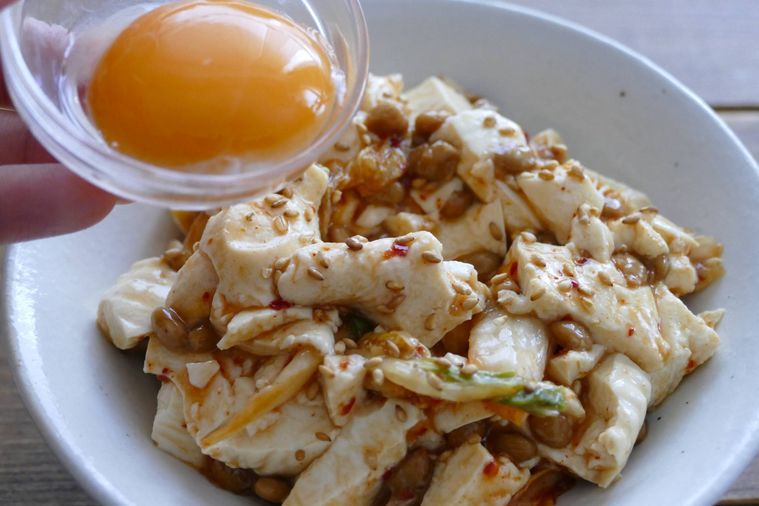 豆腐納豆キムチ和えに卵黄をトッピングしている様子