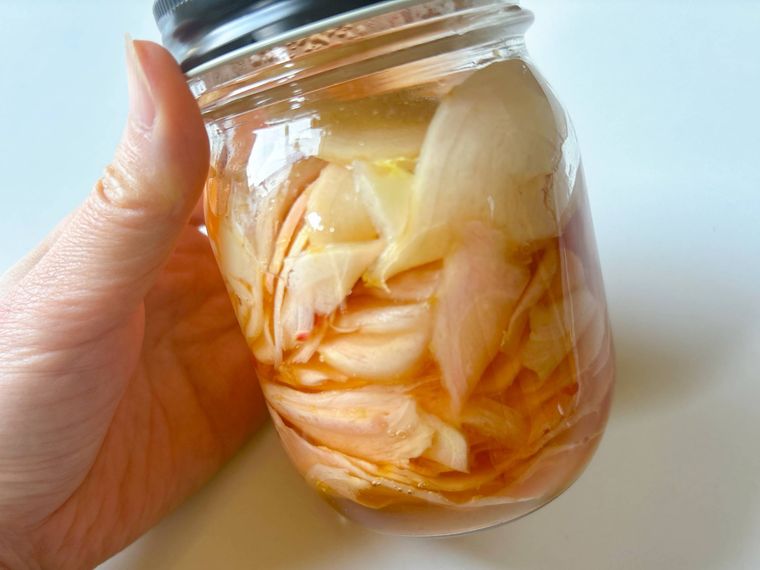 保存瓶に入った新生姜の甘酢漬けを手に持ったもの