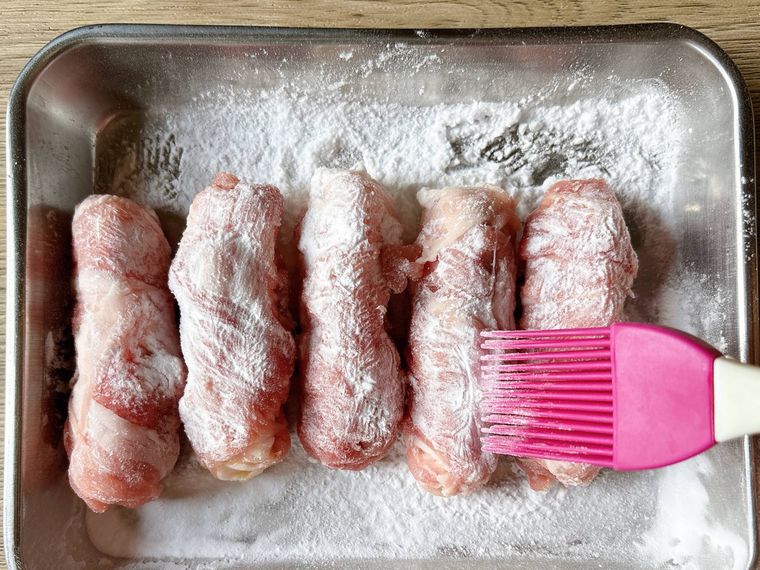 金属トレーにのせたオクラの肉巻きに片栗粉をふったもの