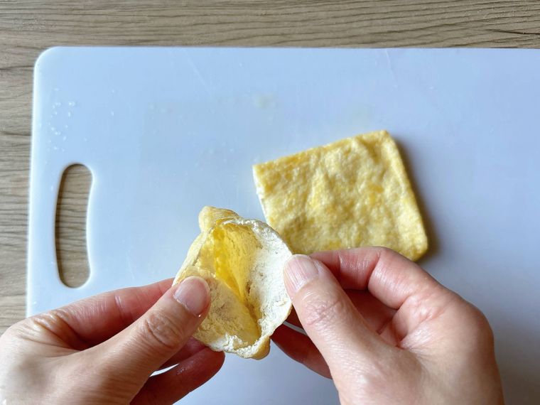 半分にカットした油揚げを袋状に開く様子