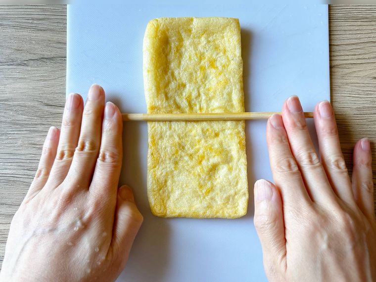 油揚げに菜箸を押し付けながら転がす様子