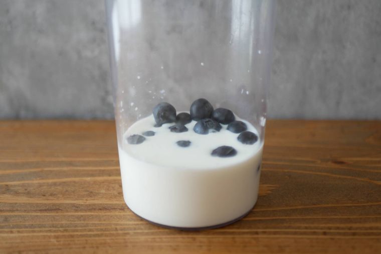 透明の容器にブルーベリーやヨーグルトなどスムージーの材料が入っている