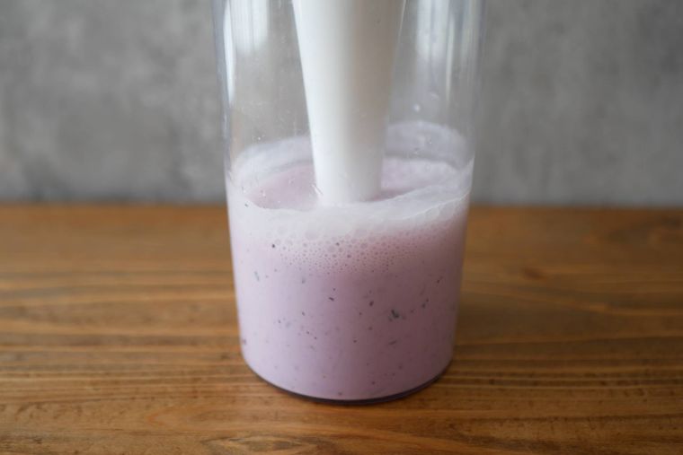 透明な容器の中でブルーベリーヨーグルトスムージーを混ぜる様子