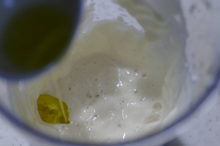 オリーブオイルを少量ずつ加える様子