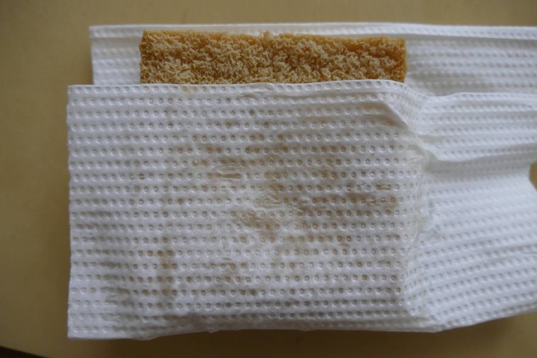 キッチンペーパーで厚揚げをはさんで油を拭く様子