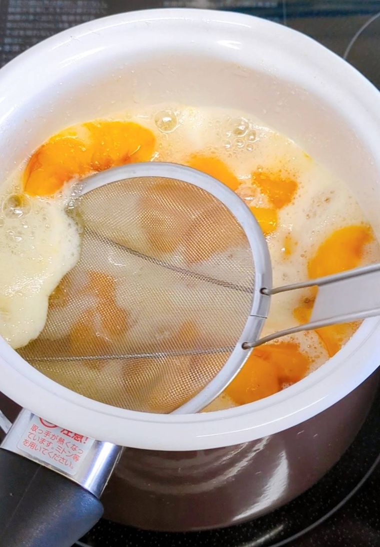 加熱中の鍋、網でアクをとっている所