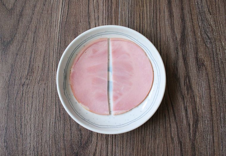 白い皿に半分にカットされたハムが置かれている様子