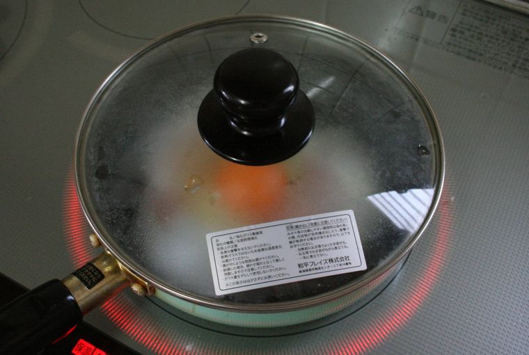 ハムエッグを作っているフライパンにフタをしている様子