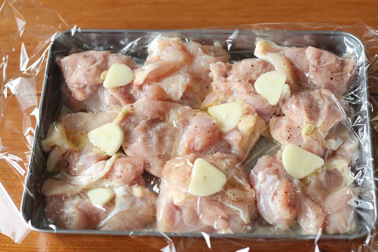 鶏肉とにんにくが入ったバットにラップを貼っている