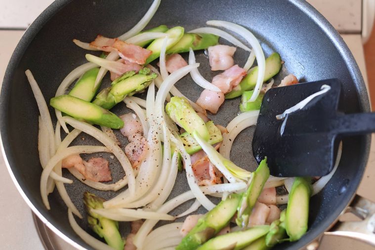 フライパンでベーコンと野菜を炒めている