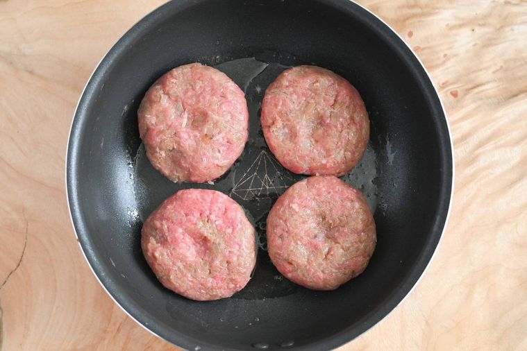フライパンに入った加熱前のハンバーグ