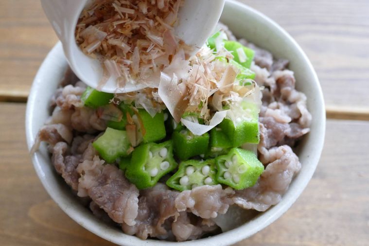 牛丼を盛り付けてかつおぶしをかける様子