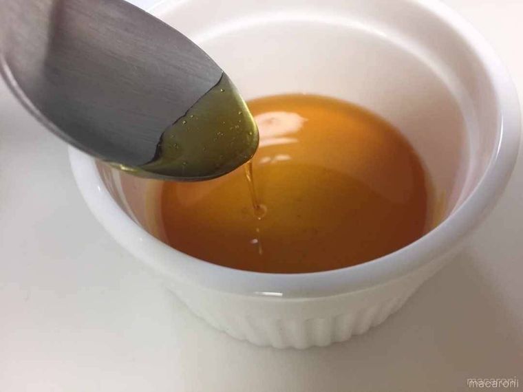 白い容器に入ったカラメルソースを、スプーンですくっている様子