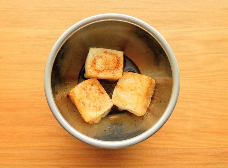 ボウルに入った調味料に揚げ餅を絡めている様子