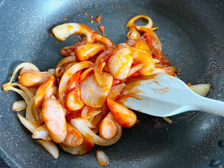 ケチャップを加えてウインナーソーセージと玉ねぎを炒める様子