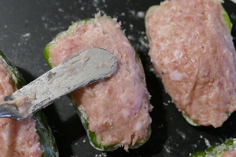 ピーマンに肉だねを詰め込む様子