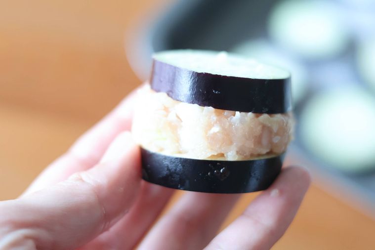 肉だねをはさんだなすを手で持っている