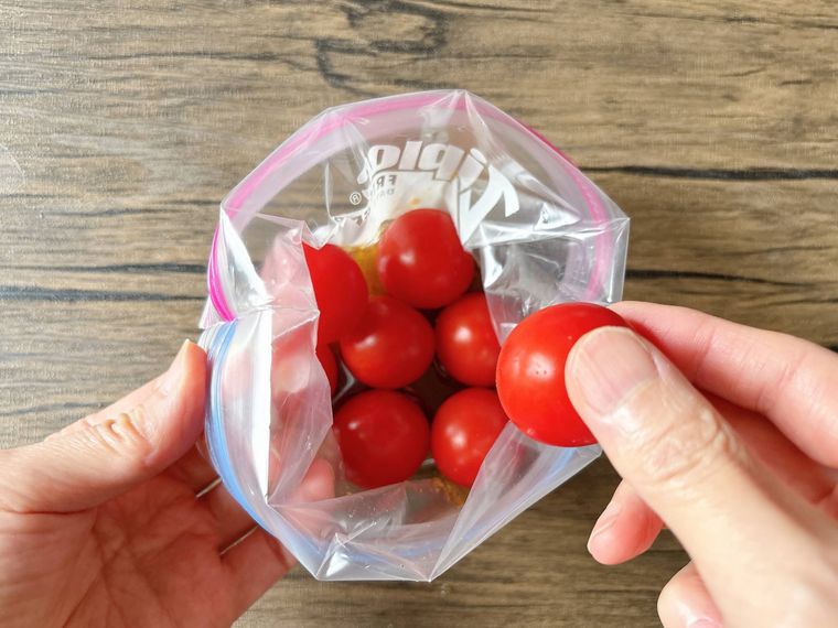 調味料が入ったジッパー付き保存袋にミニトマトを入れる様子