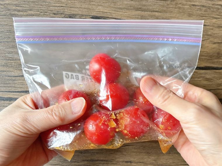 ミニトマトが入ったジッパー付き保存袋の上から揉む様子