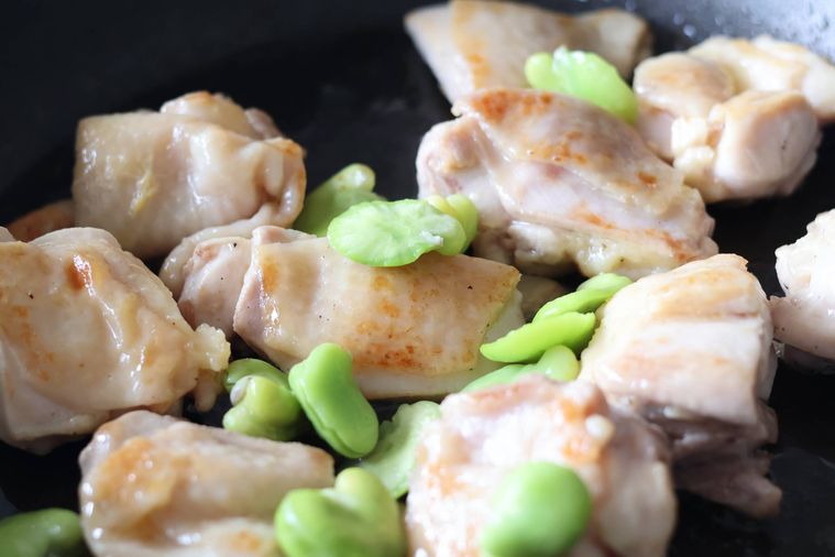 フライパンで鶏肉とそら豆を炒めている