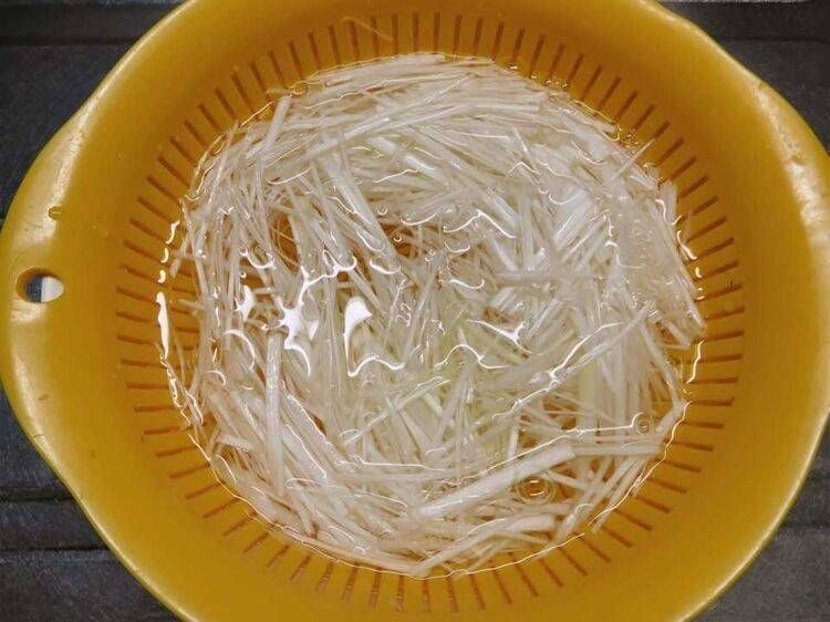 黄色いザルを使って、白髪ねぎを水にさらしている
