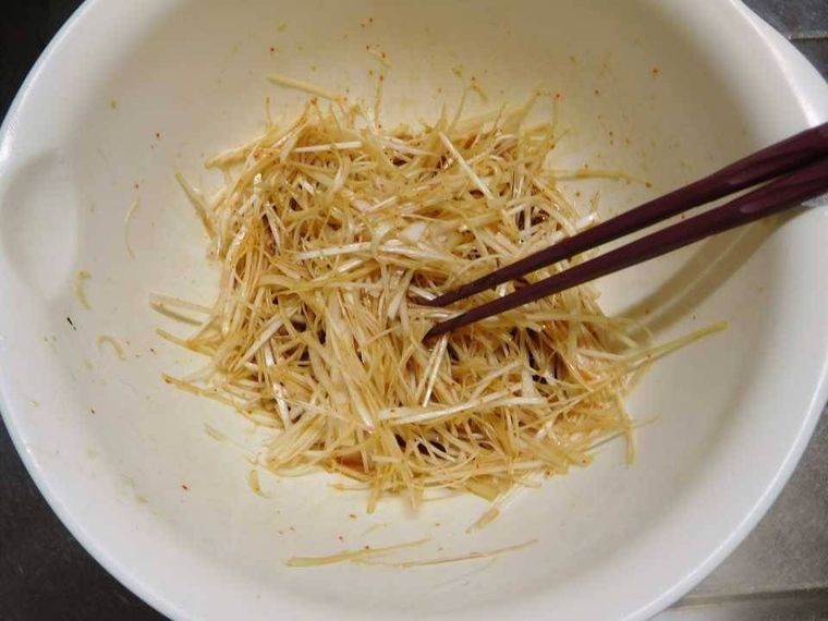 白いボウルのなかで、白髪ねぎを調味料と和えている