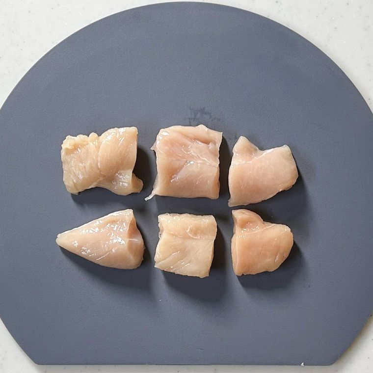 グレーのまな板の上に乗る3等分にされた鶏ささみ2本
