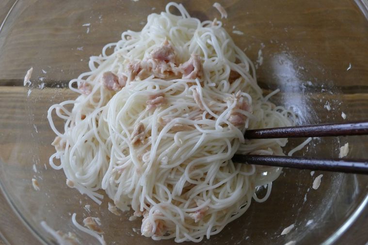 そうめんにツナ缶オイル漬けを加えて箸で和える様子