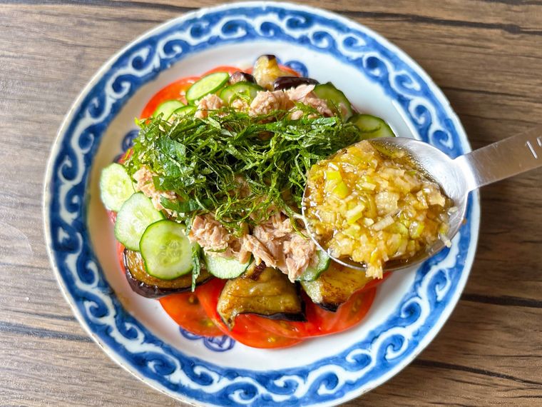 トマト、揚げなす、きゅうり、ツナ缶を盛り付けたものにバンバンジーたれをかける様子