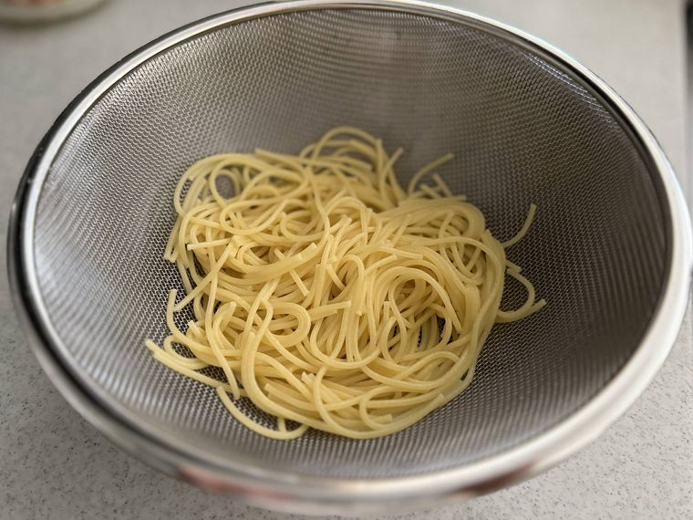 茹で上がったスパゲティをザルにあげている。