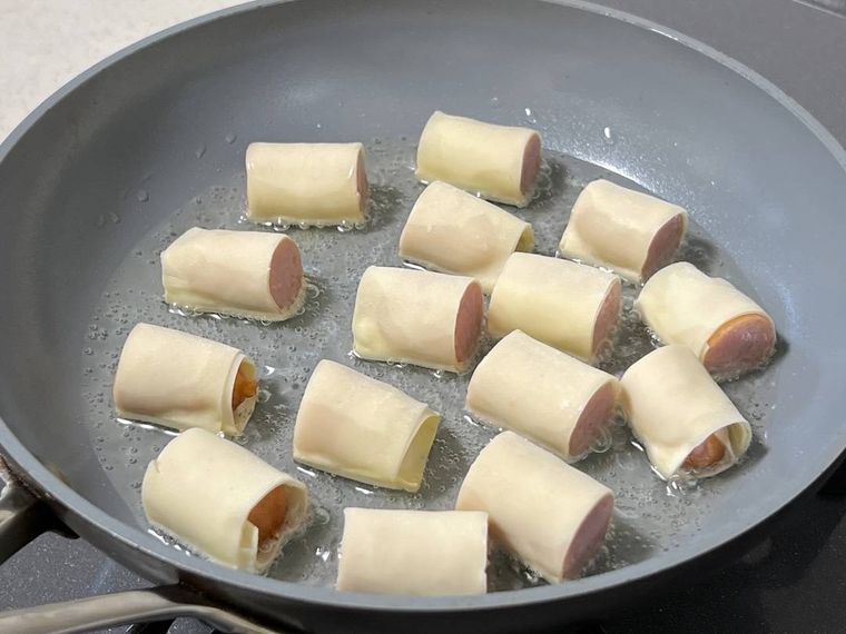 ワンタンの皮で巻いたウインナーソーセージを揚げ焼きにしている様子