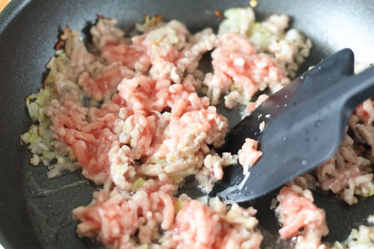 フライパンで香味野菜と豚ひき肉を炒めている