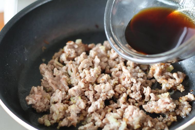 そぼろの入ったフライパンに調味料を入れている