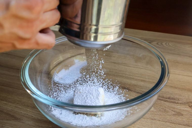 バターの入ったボウルにふるい入れている