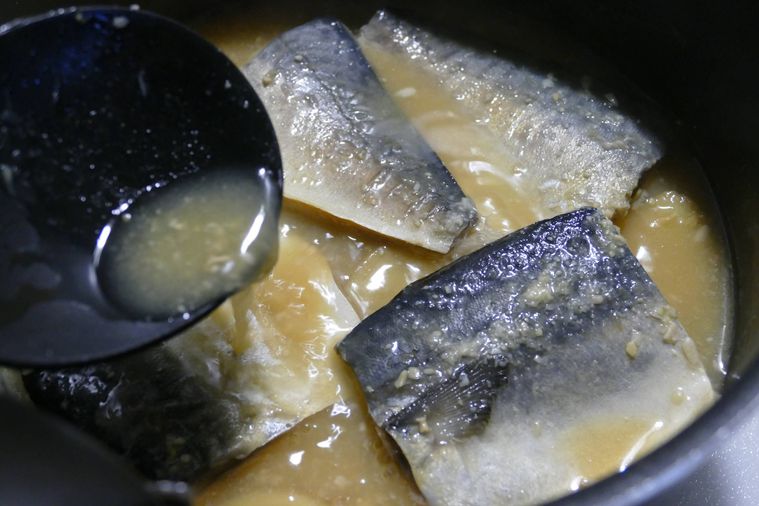 煮汁をさばにかけながら煮込む様子