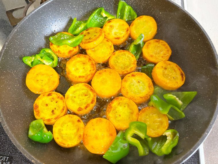 調味料を黄色ズッキーニやピーマンに絡める様子