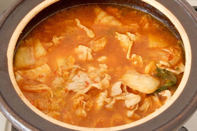 土鍋で豚ロース肉と白菜キムチを煮ている様子