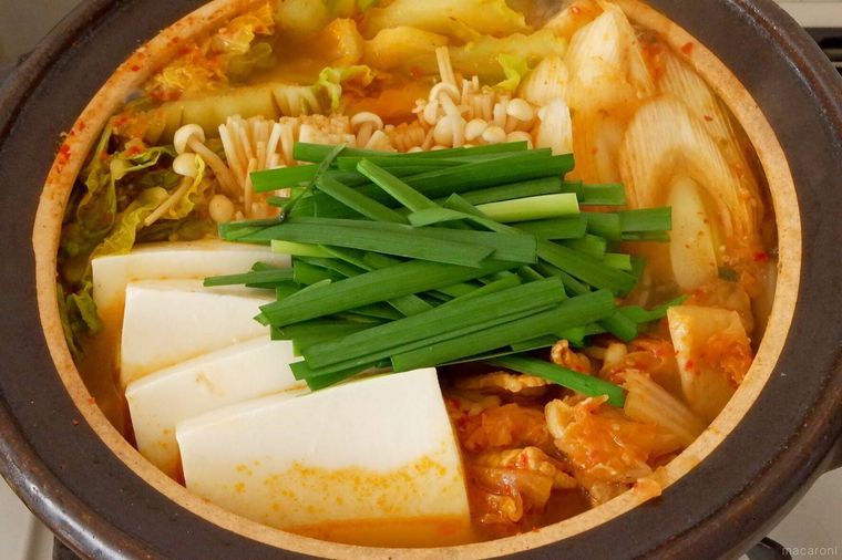 土鍋で絹豆腐とニラ入りのキムチ鍋を煮ている様子