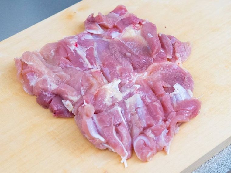 木製まな板の上に置かれた鶏もも肉