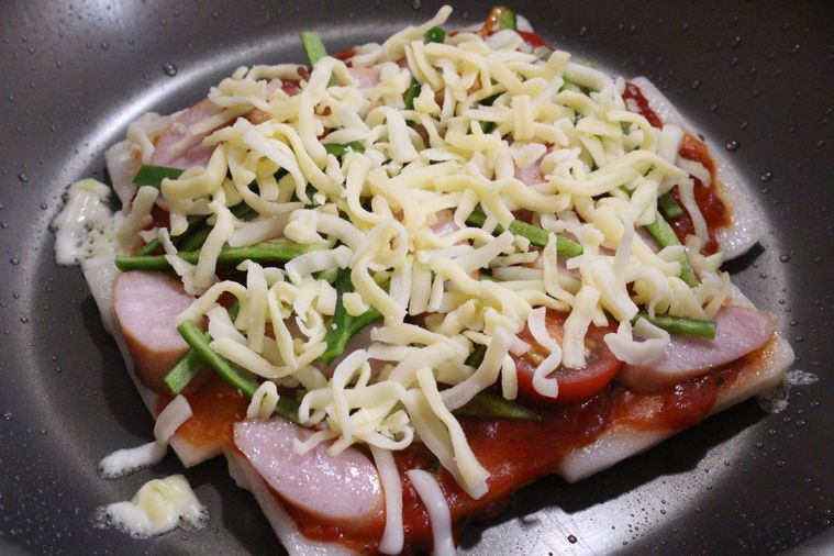 フライパンで焼いた餅の上に具材をのせている様子