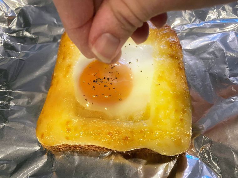 エッグマヨネーズトーストに粗挽きこしょうをかける様子。