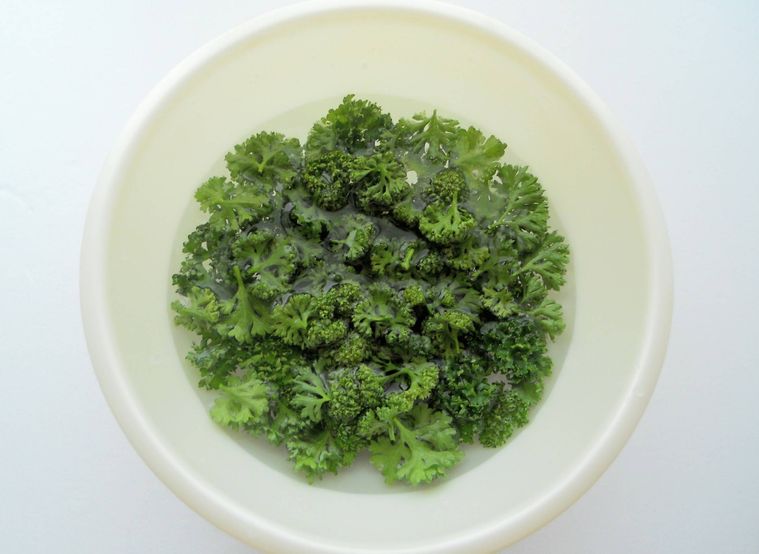 白いボウルの水の中に入った、パセリの葉先