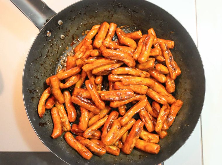 フライパンでかりんとうを黒糖の糖衣に絡める様子