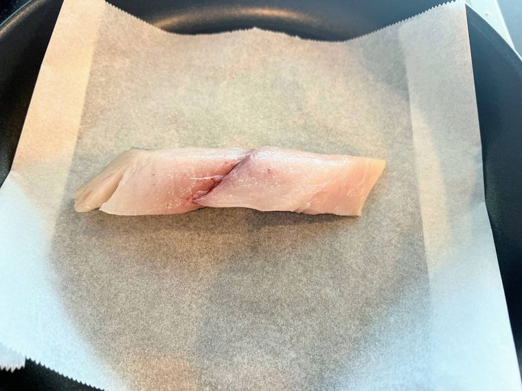 クッキングシートを敷いたフライパンで魚の切り身を焼く様子