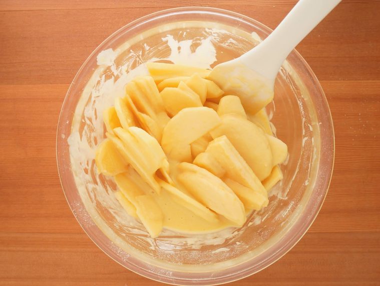 スライスしたりんごを加えて、ゴムベラで混ぜる様子