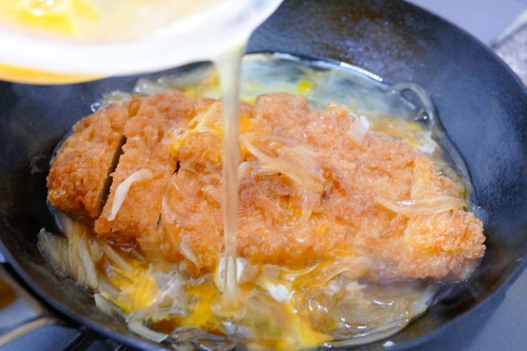 溶き卵をフライパン全体にまわしかける様子