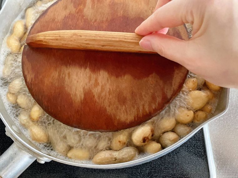 落花生をゆでている鍋に落とし蓋をする様子